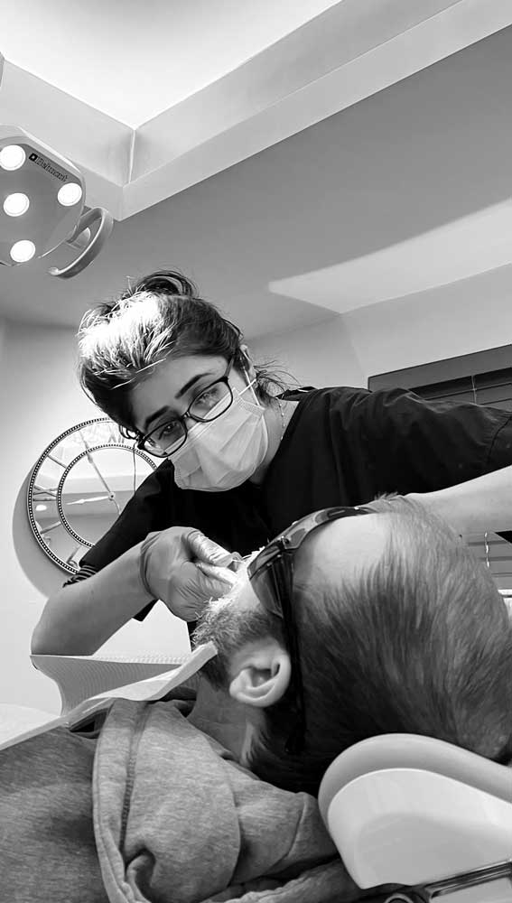 Dental hygienist performing check-up on male patient at Hewett's Dental clinic in Brighouse, Huddersfield, Halifax, Bradford, modern dental practice, professional dental care, patient comfort, dental treatment room.